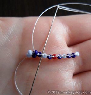 String a single bead onto the thread. Slide the needle underneath the next thread bridge