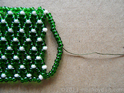 Bring the needle back halfway through the beads