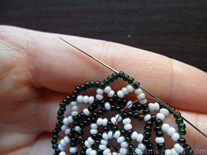 Push the needle through the beads in the outermost row so that it comes out in the middle of one of the petals