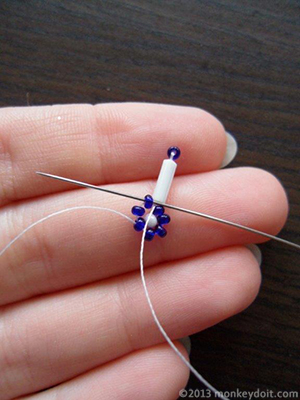 Push the needle through the neighbouring seed bead from the centre of the star