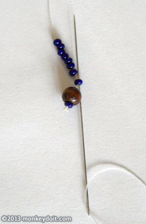 String 8 beads onto the thread and push the needle back through the first bead to create a loop