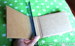 A ruler is used to score a binding area of the cardboard